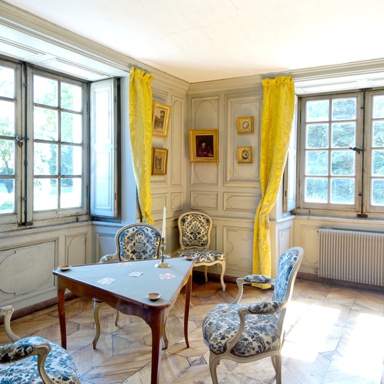 chambre du roi est meublée et décorée dans un style 18e siecle avec des rideaux jaunes