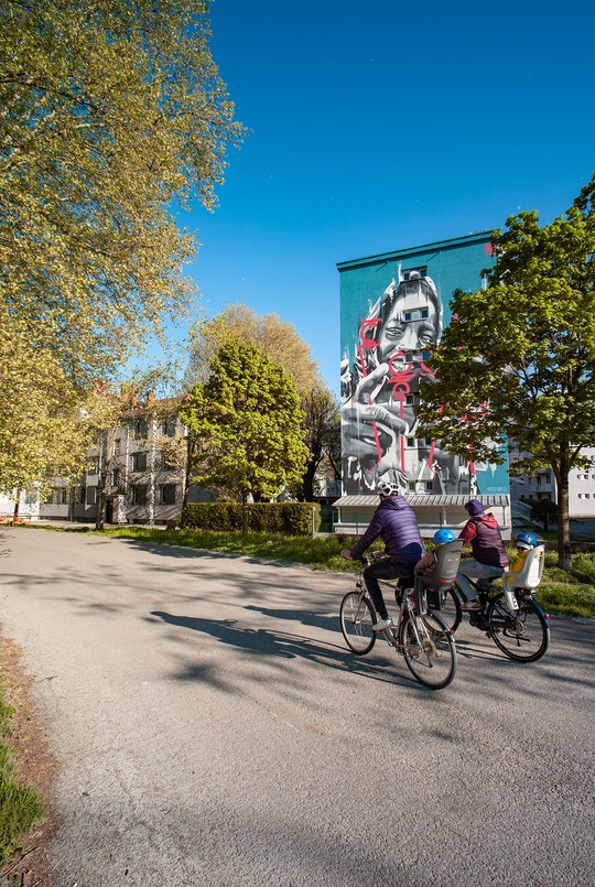 Cyclistes pistes cyclables arbres immeubles oeuvres colorées street art